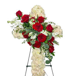 Cross-shaped floral spray with red and white roses on a stand