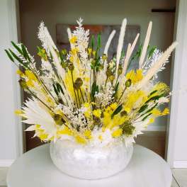 Large white and yellow floral arrangement in a round white vase