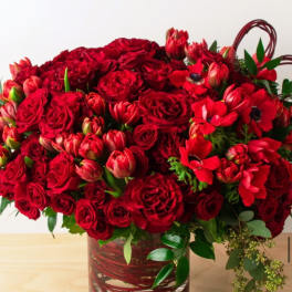 Red roses and red tulips arranged in a glass vase