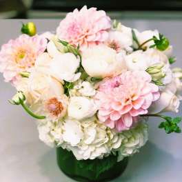 Pink and white flowers arranged in a green glass vase