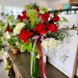 Bouquet of red roses and white hydrangeas with ribbon in a glass vase