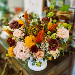 Mixed bouquet in a white vase with peach, yellow, and burgundy flowers