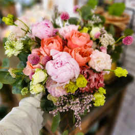 Handheld bouquet of pink and peach flowers with small accent blooms