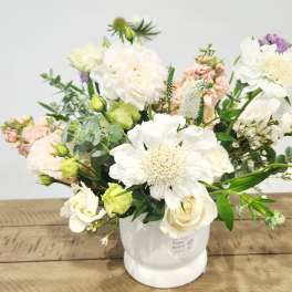 White and blush mixed flower arrangement in a white vase