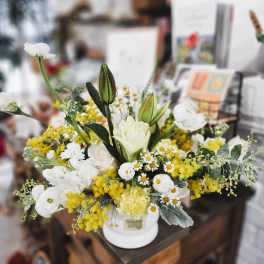 White and yellow floral arrangement in a white vase