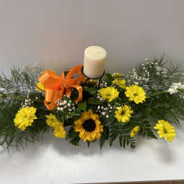 Yellow daisy and sunflower arrangement with a candle and orange ribbon