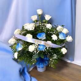 White and blue roses arranged in a vase with a ribbon