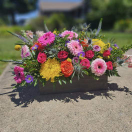 Colorful mixed flower arrangement in a rectangular wooden container