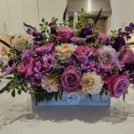 Pink and purple floral arrangement in a rectangular wooden box