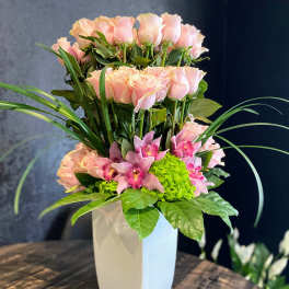 Pink roses and orchids arranged in a white vase