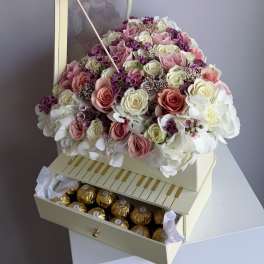 Heart-shaped box of pink and white roses with chocolates in a drawer and a purple butterfly decoration.