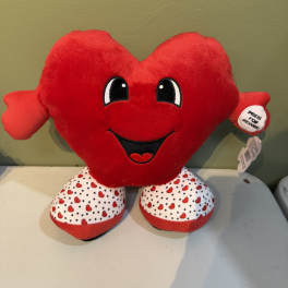 Red heart-shaped plush toy with a smiling face and patterned feet