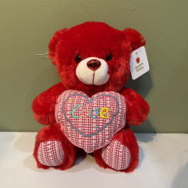 Red teddy bear holding a heart with the word love