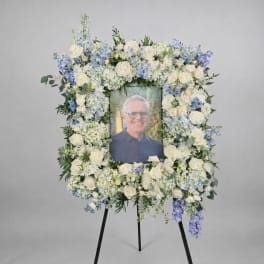 Tall rectangular floral photo frame with white and light blue flowers on a black easel.