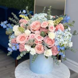 Pink and white roses with blue hydrangeas in a light blue vase