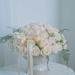White rose arrangement in a textured vase with a ribbon bow