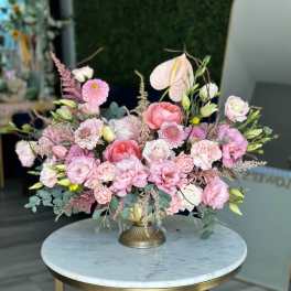 Pink and white floral arrangement in a gold pedestal vase