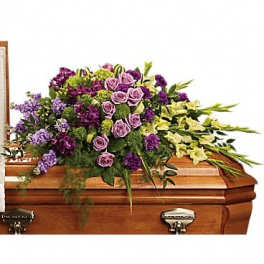 Purple and lavender floral spray on a wooden casket