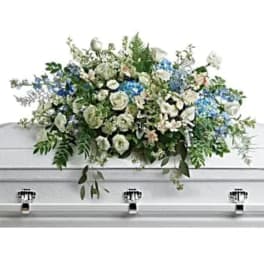 White casket spray with blue flowers and greenery