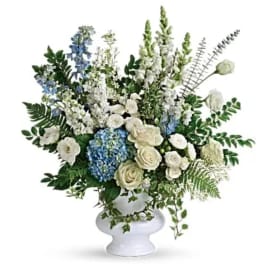 White and blue floral arrangement in a white pedestal vase