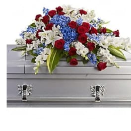 Red roses, white lilies, and blue flowers arranged on a silver casket