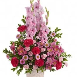 Pink and red floral arrangement in a woven basket