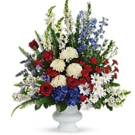 Red roses, white flowers, and blue blooms in a white vase