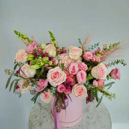Pink and cream rose bouquet in a pink hat box with a ribbon