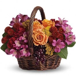 Basket of orange roses and purple flowers with grapes