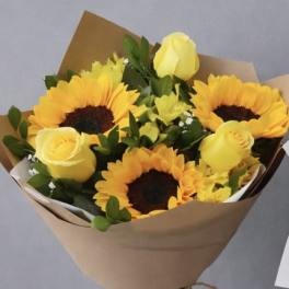 Bouquet of yellow sunflowers and roses wrapped in brown paper