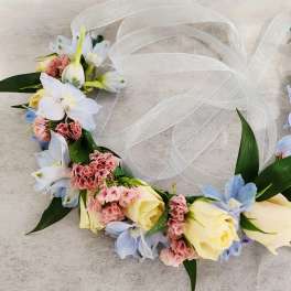 Floral crown with pale roses, blue flowers, and white ribbon
