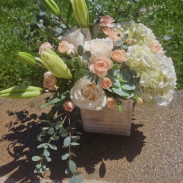Bouquet of white and peach flowers in a wooden box