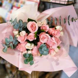 Pink rose bouquet wrapped in pale pink paper with eucalyptus