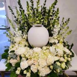 White floral arrangement surrounding a round white urn