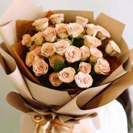 Bouquet of pale peach roses wrapped in brown paper