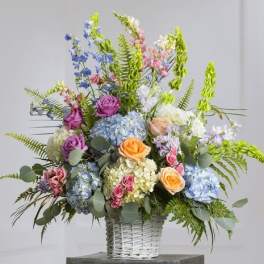 Mixed bouquet in a white wicker basket with roses and hydrangeas