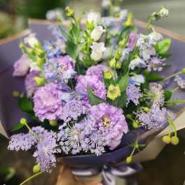 Lavender and white bouquet with airy blue flowers wrapped in dark paper