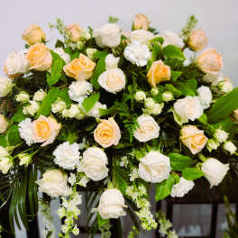 Large arrangement of pale peach and white roses with greenery