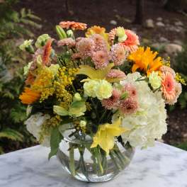 Mixed bouquet in a clear glass vase with white hydrangeas and orange daisies