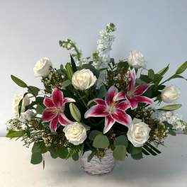 White roses and pink lilies in a white basket vase