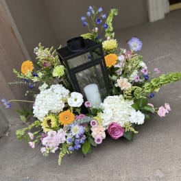 Floral wreath with a black lantern and white candle in the center