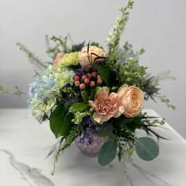 Mixed bouquet of peach and pale blue flowers in a vase