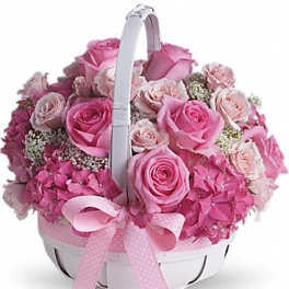 Pink roses and hydrangeas arranged in a white basket with a ribbon
