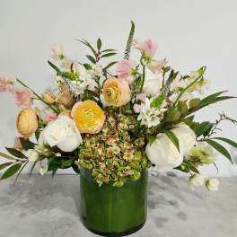 Mixed bouquet in a green glass vase with white, pink, and yellow blooms