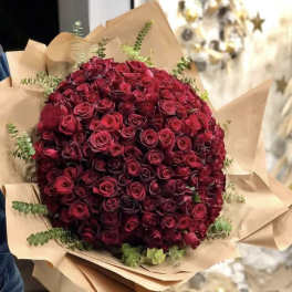 Large bouquet of deep red roses wrapped in brown paper