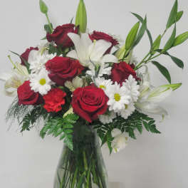 Bouquet of red roses, white lilies, and daisies in a glass vase