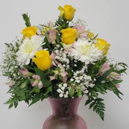 Yellow roses and white daisies in a pink vase