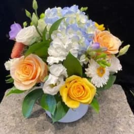 Mixed bouquet with pastel roses, hydrangea, and daisies in a round vase
