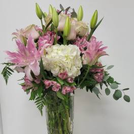 Pink lilies and white hydrangea in a clear glass vase