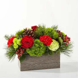 Red roses and carnations in a wooden box with pinecones and greenery